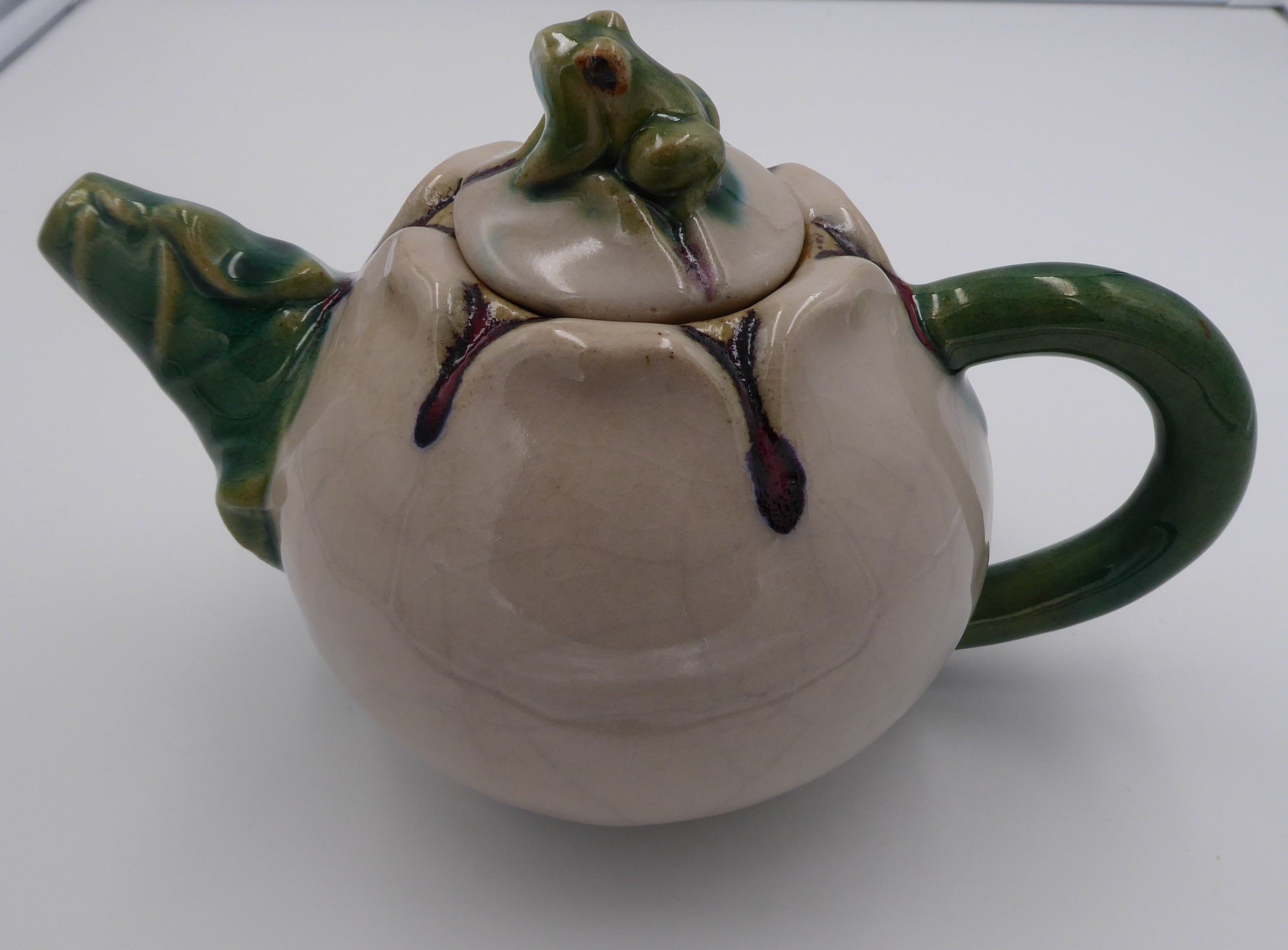 Théière en céramique beige surmontée d'une grenouille