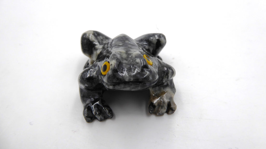 Petite grenouille en pierre tachetée aux yeux jaunes