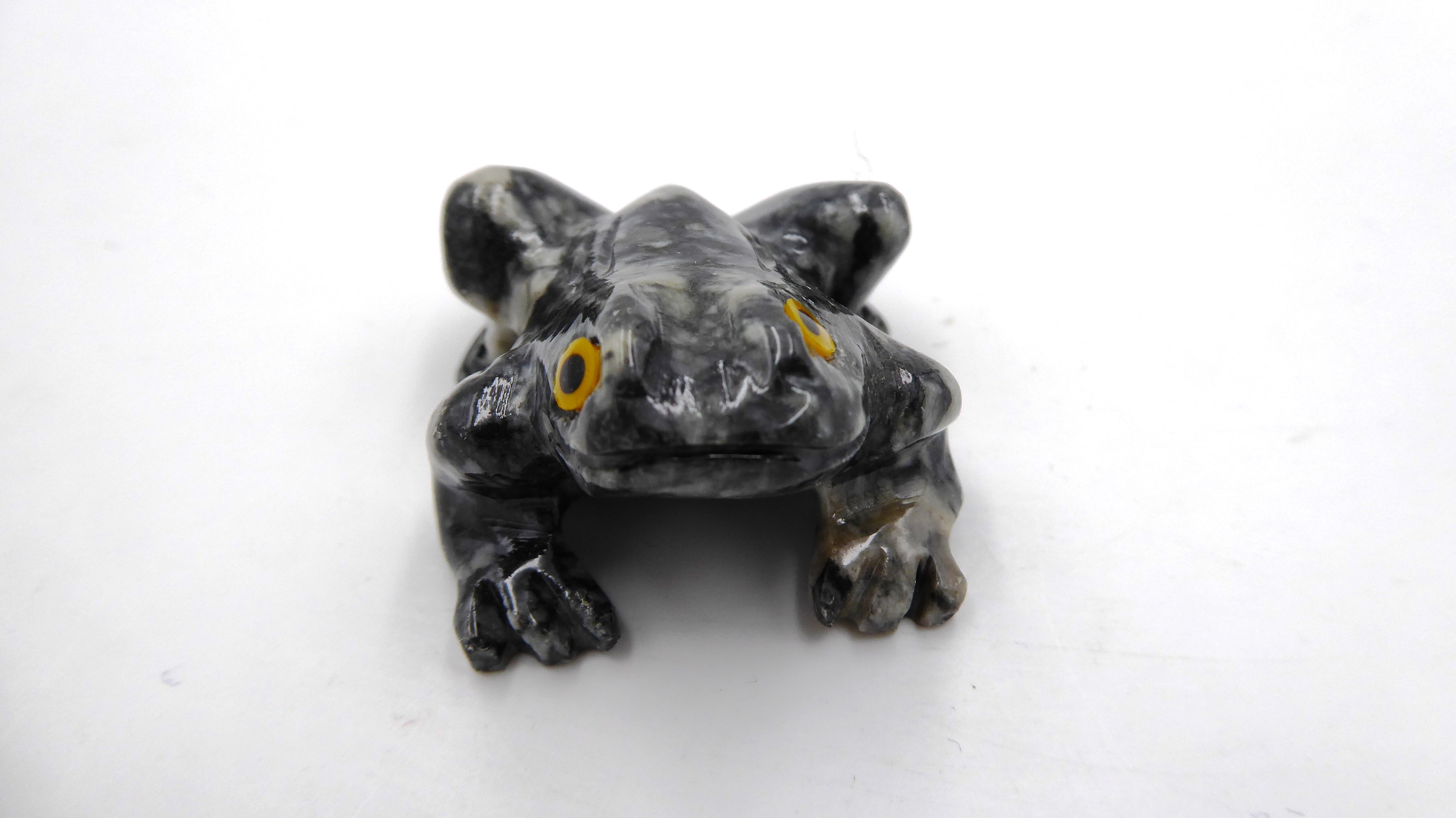 Petite grenouille en pierre tachetée aux yeux jaunes