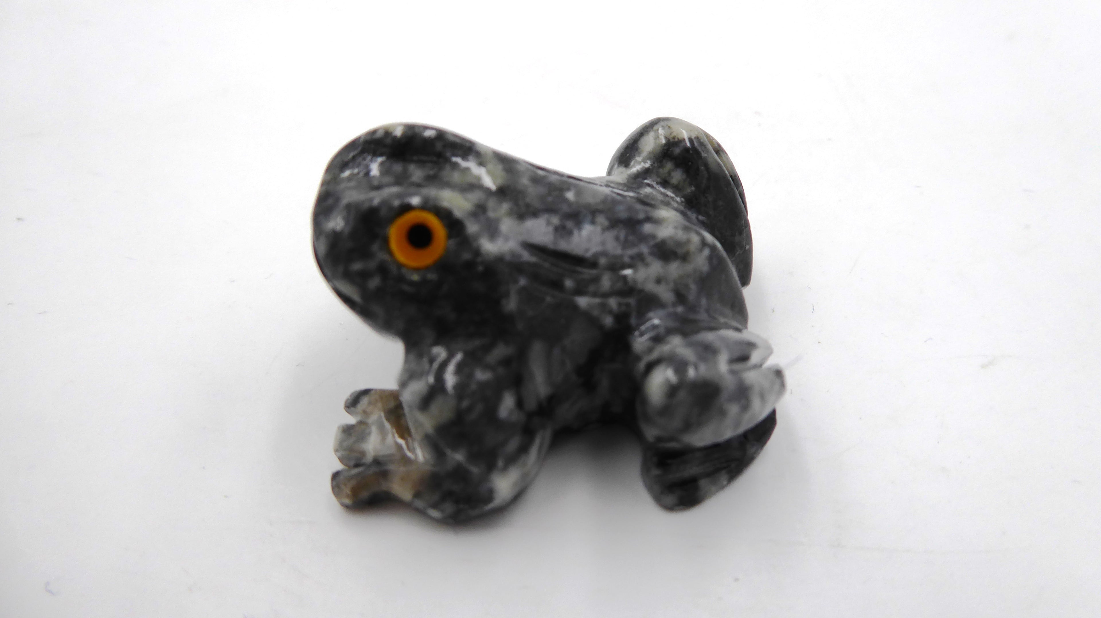 Petite grenouille en pierre tachetée aux yeux jaunes