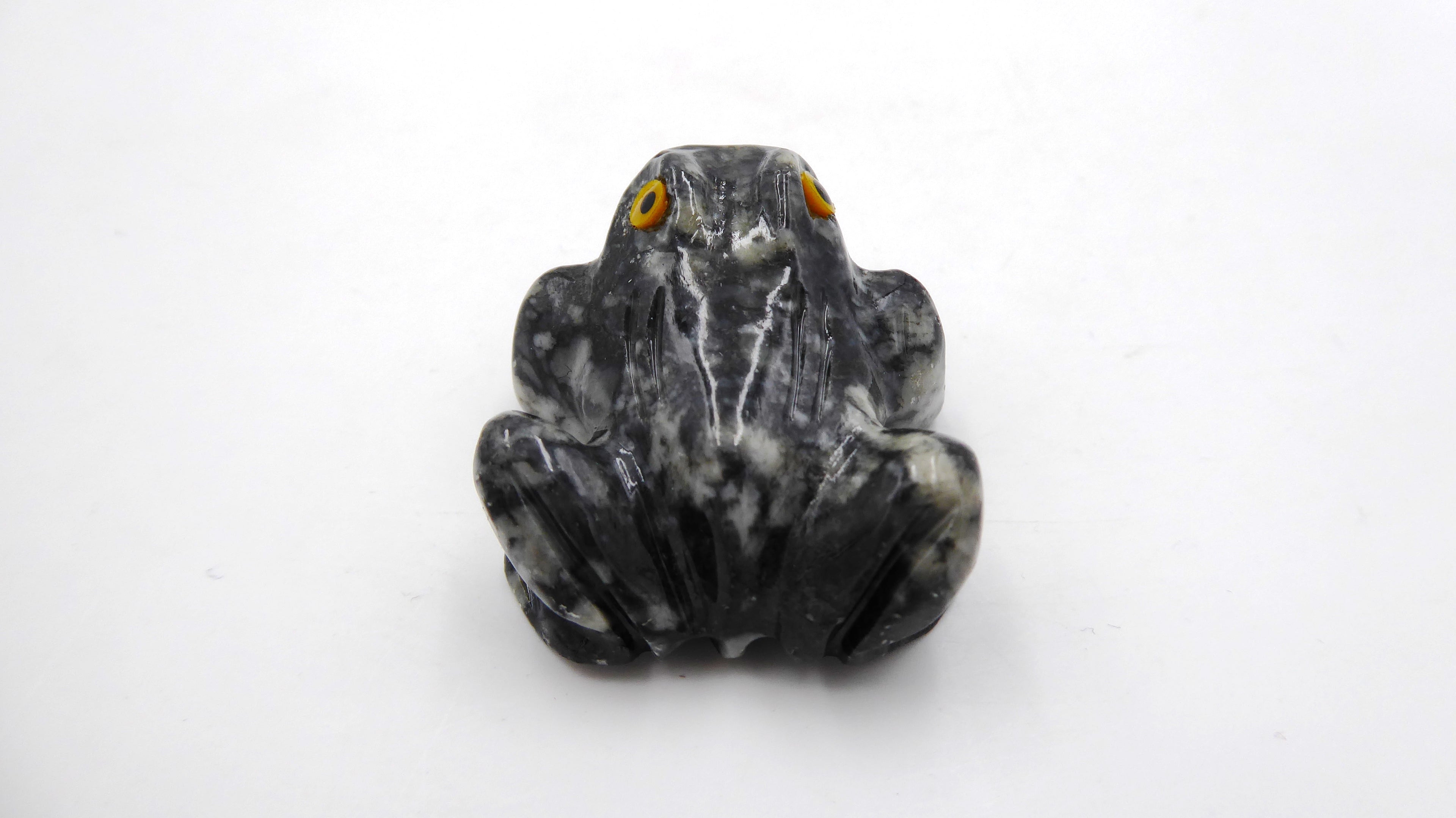 Petite grenouille en pierre tachetée aux yeux jaunes
