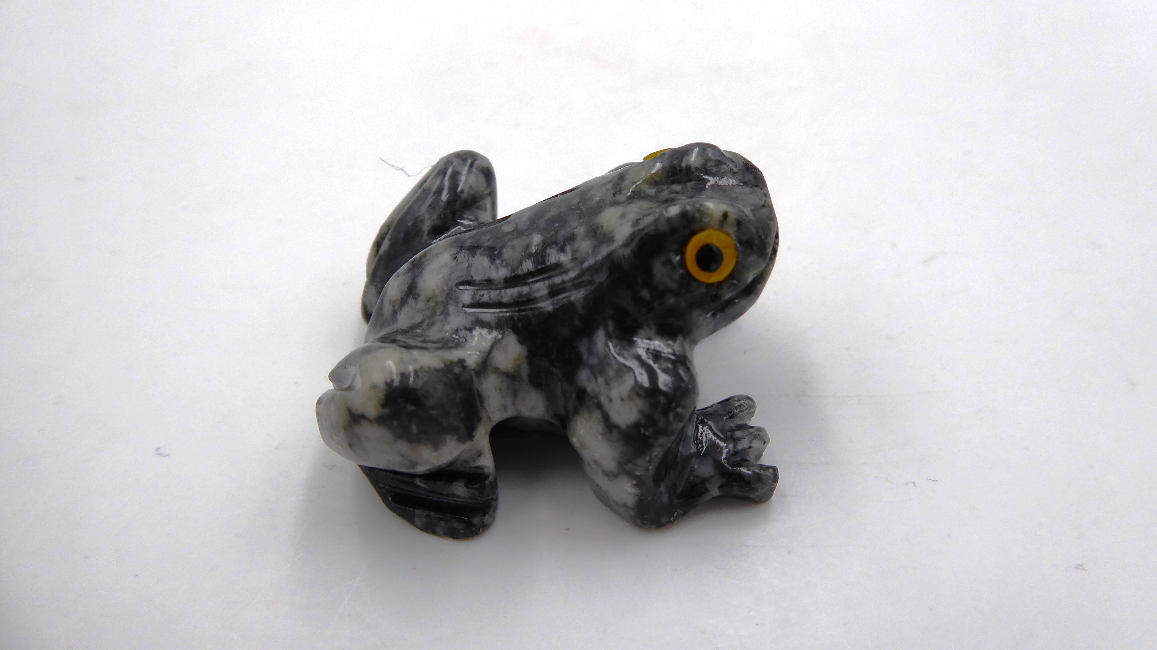 Petite grenouille en pierre tachetée aux yeux jaunes