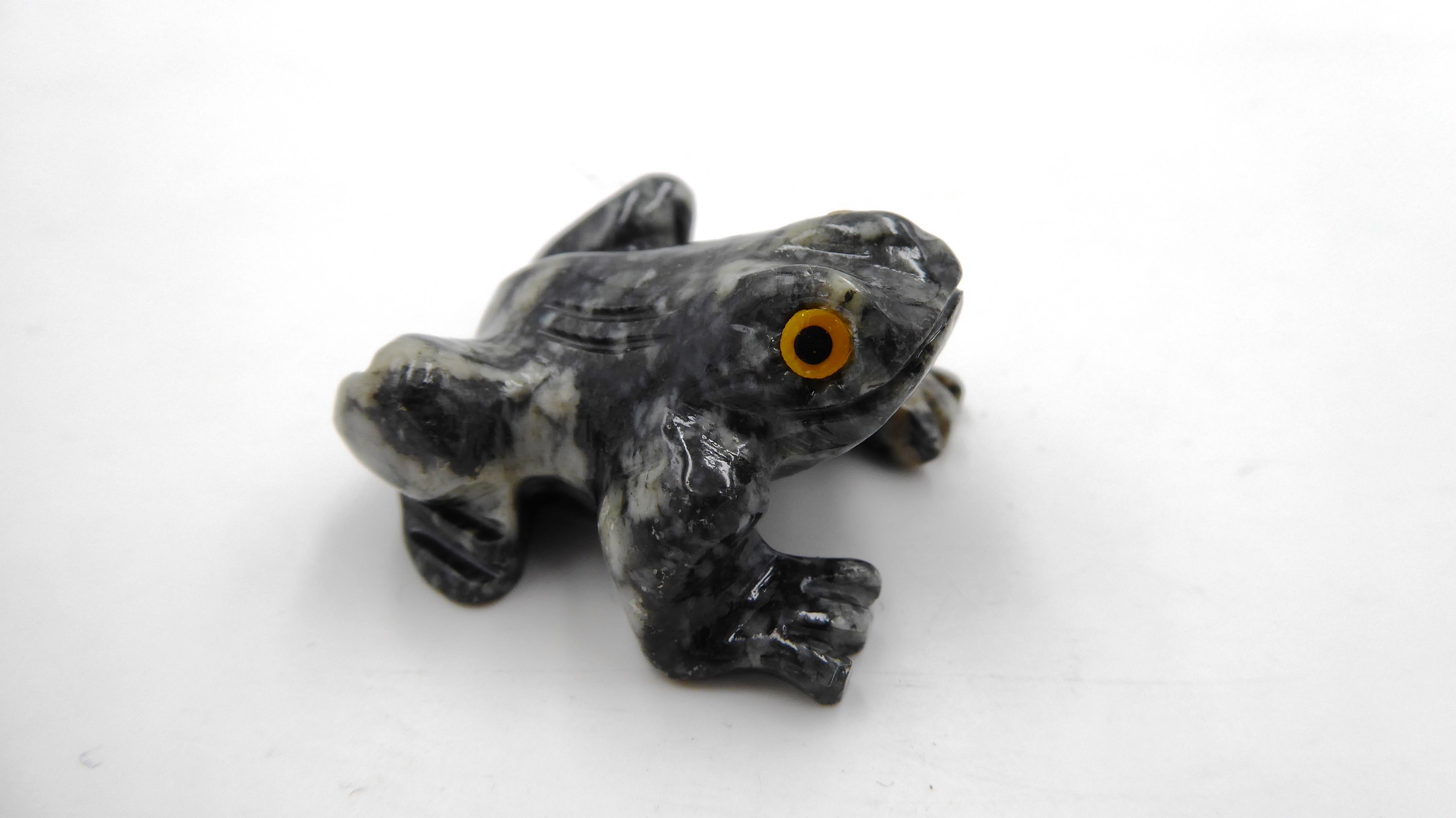 Petite grenouille en pierre tachetée aux yeux jaunes