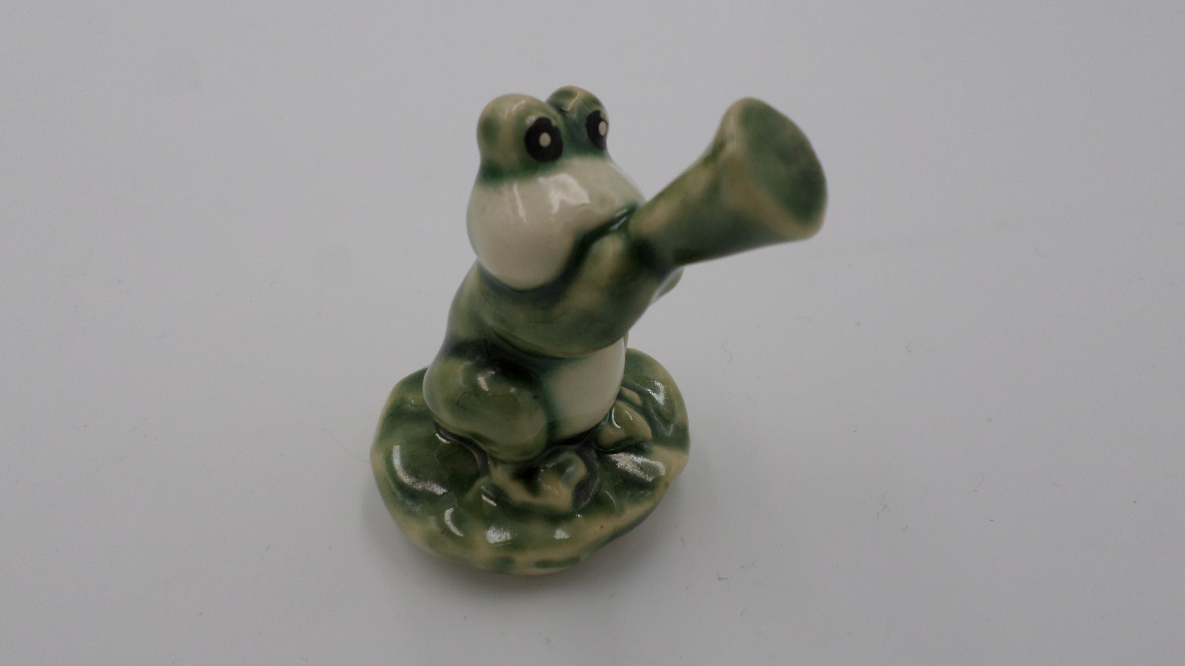 petite grenouille en céramique jouant de la flute