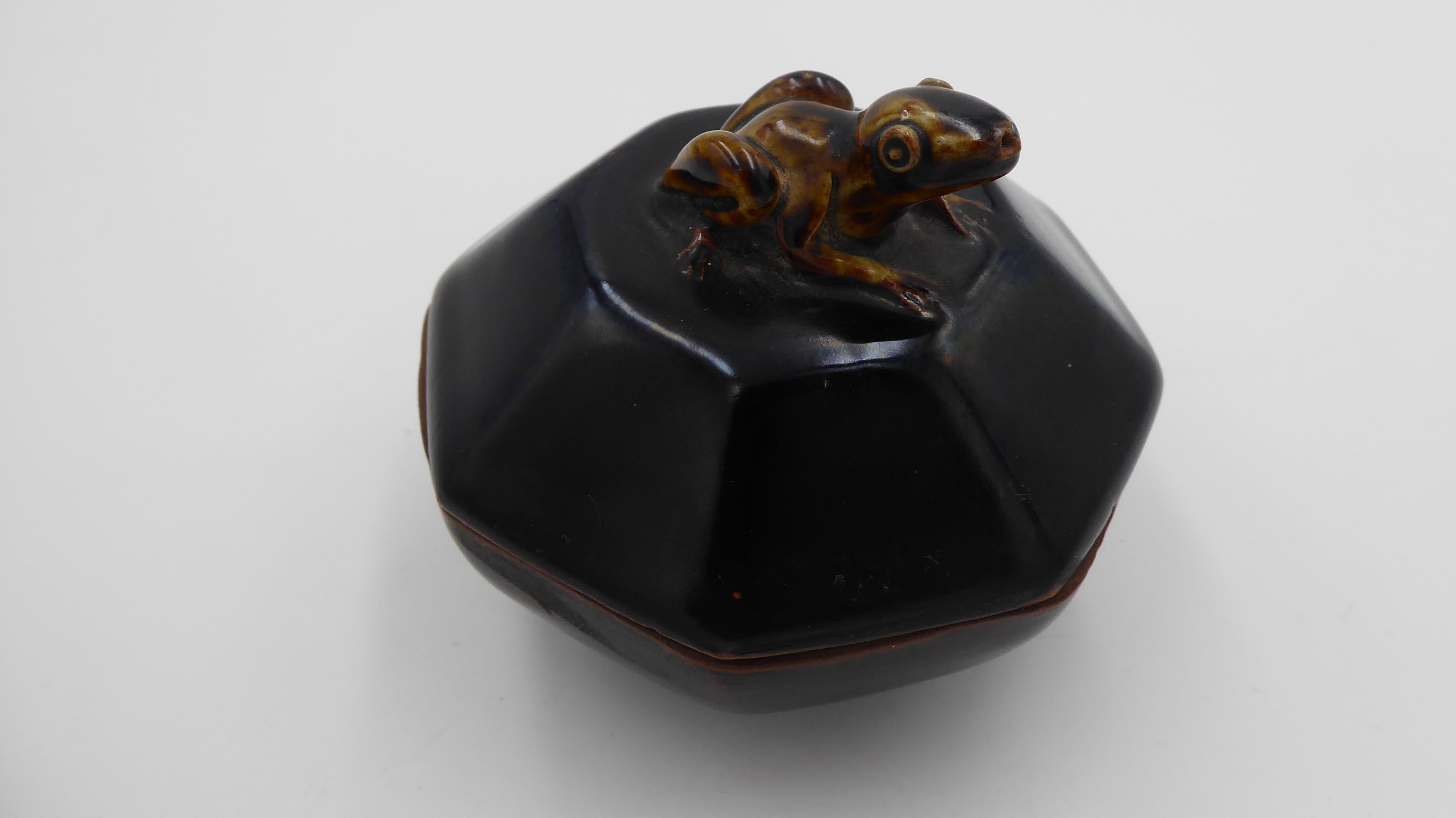 Vieux pot en céramique surmonté d'une grenouille
