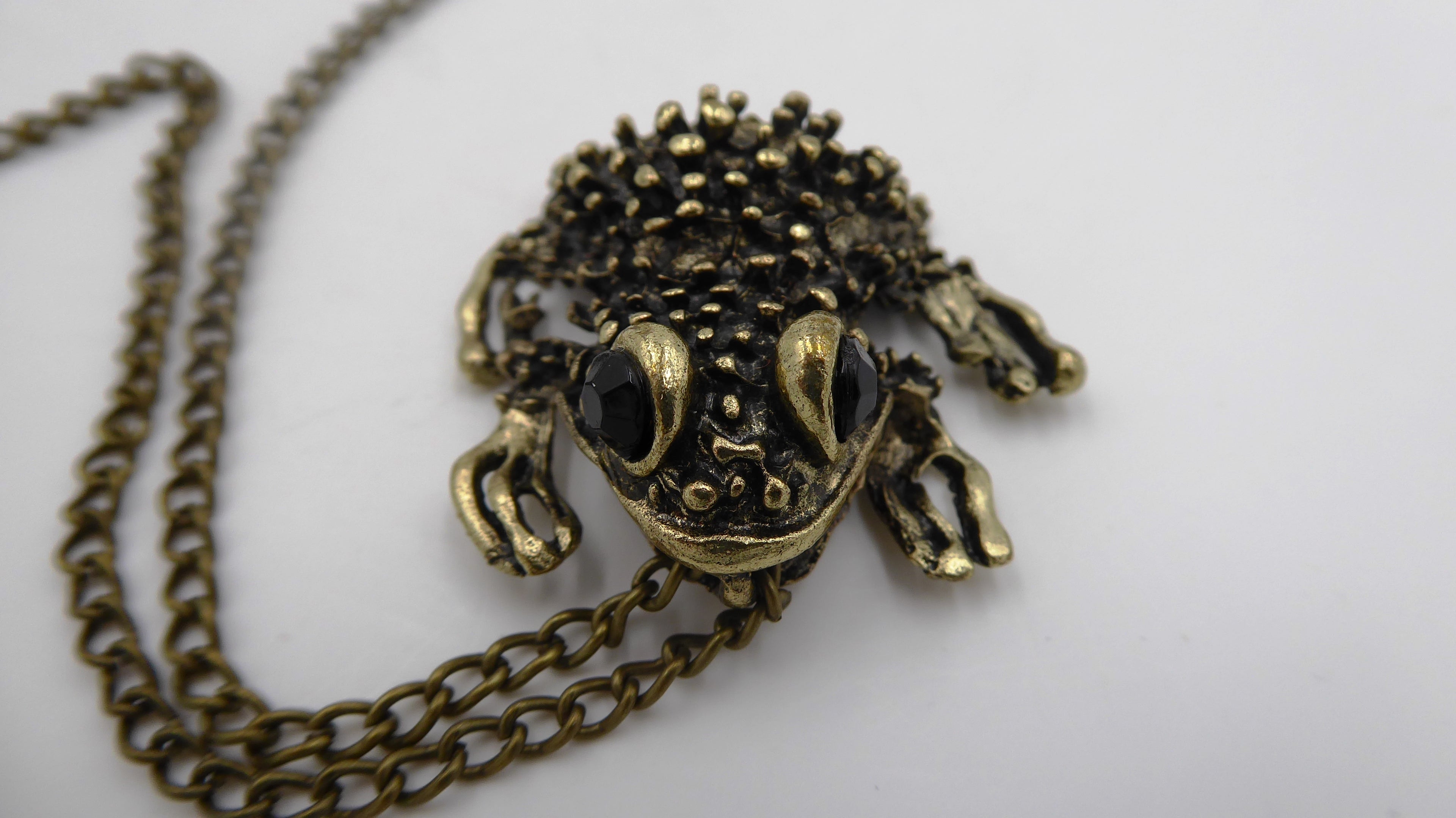 Pendentif ancien métal doré noirci (Laiton ?) avec deux yeux en brillants biseautés