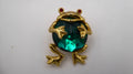 Broche grenouille en métal doré incrusté d'une pierre à facette