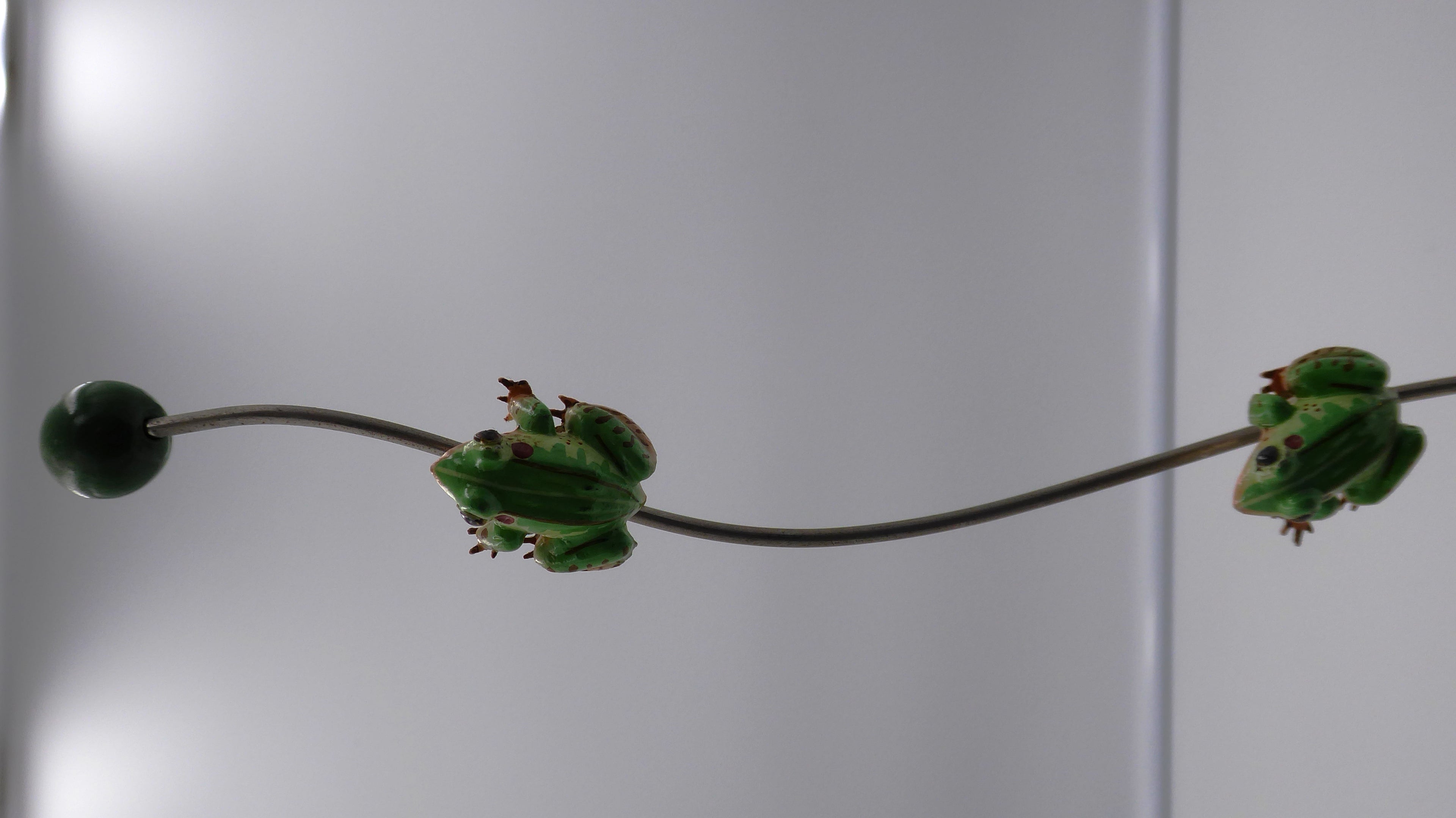Trois petites grenouilles alimentées montant sur une tige supportée par une grenouille